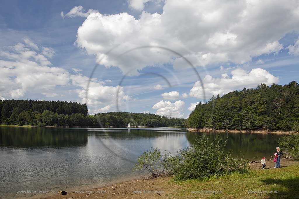 Bevertalsperre mit Landschaft, Segelboot, Kumuluswolken und Speigelbild. Familie, Frau mit Kindern am Ufer; Bever dam, lake with sailboat and cumulus clouds with mirror image, family with a wife and two children at lakeshore