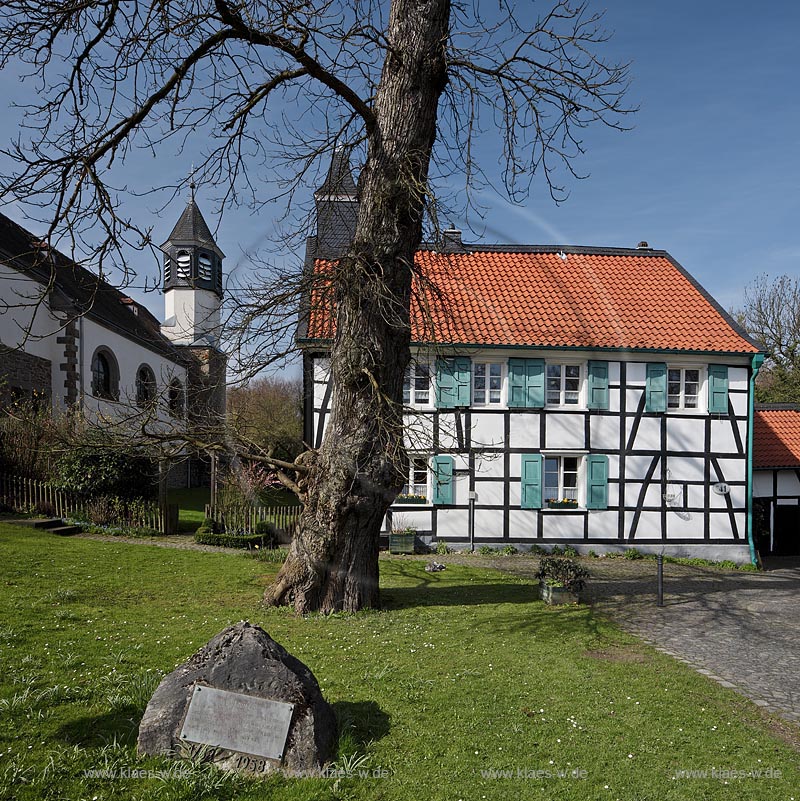 Heiligenhaus-Hetterscheid, Abtskueche. Die 1908/09 erbaute Kapelle war nicht das erste Gotteshaus in der Abtskche. Am Trmchen auf dem direkt nebenan liegenden Fachwerkhaus ist erkennbar, dass dort zuvor eine Kapelle stand. Dieses Fachwerkhaus war 1783 als Schule errichtet worden und hatte 1792 einen Anbau erhalten, der - heute nicht mehr sichtbar  den Hauptschulraum um eine Apsis erweiterte. Dieser erweiterte Raum wurde 1792 als Kapelle eingeweiht; Heiligenhaus Hetterscheid, Abtskueche, halt umbered ofd schoolhouse and chapel in Springime