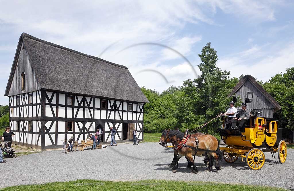 Lindlar Bergisches Freilichtmuseum Lindlar fuer Oekologie und baeuerlich-handwerkliche Kunst, nachgebaute historische Postkutsche, Nachbildung zweispaennig von 2 Kaltblut Pferden gezogen faehrt durch das Museum wahrend der Veranstaltung Jroen und Jedoen Garten und Pflanzenmarkt mit Besuchernam historischen Fachwerkhof Hot zum Eigen mit Reetdach;  Lindlar open-air museum with replication of a historical stagecoach