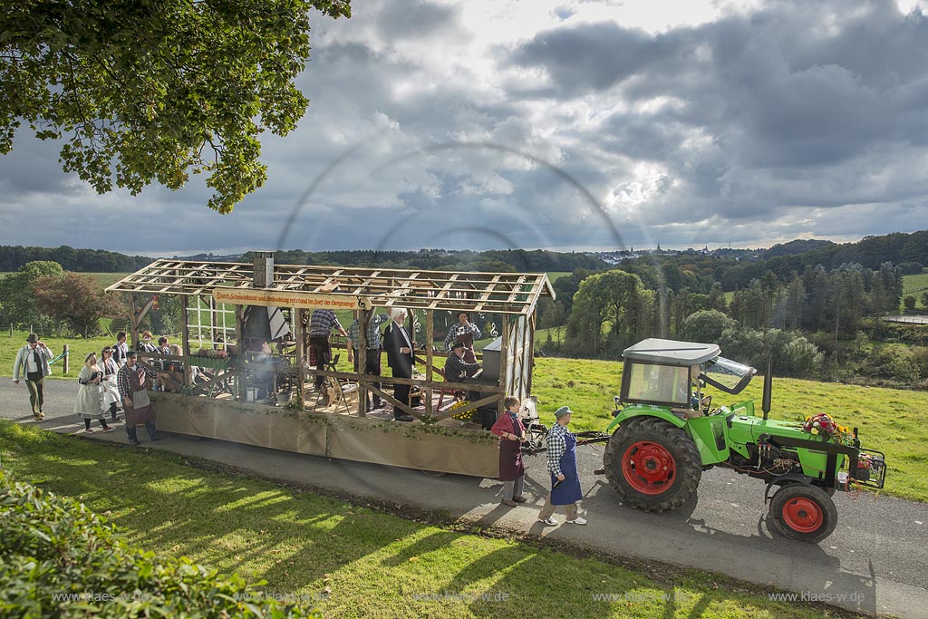 Radevormwald-Oenkfeld, Erntedankfest, Umzug mit floristisch anspruchsvoll gestaltetem und Felderzeugnissen kunstvoll dekoriertem Traktor und Erntewagen in Rochollsberg. Im fernen Hintergund die Stadtsilhouette von Radevormwald mit Ihren vier Kirchtuermen.