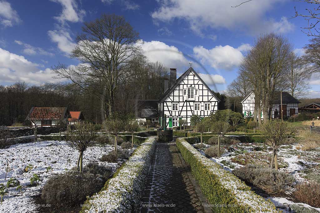 Radevormwald Lorenzhaus , Bauerngarten mit vorbildlich restauriertem Fachwerkhaus in Winterlandschaft, mit Schneeresten bei blauem Himmel mit Kumuluswolken und kahlen Baeumen, Uebergangszeit; Radevormwald half-timeberd house with farmers garden at a late winter day, rest of snow, cumulus clouds in the blue sky