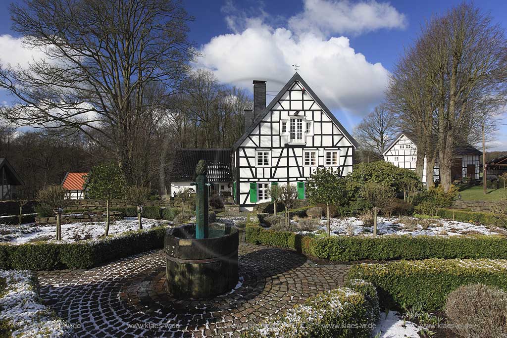 Radevormwald Lorenzhaus , Bauerngarten mit vorbildlich restauriertem Fachwerkhaus in Winterlandschaft, mit Schneeresten bei blauem Himmel mit Kumuluswolken und kahlen Baeumen, Uebergangszeit; Radevormwald half-timeberd house with farmers garden at a late winter day, rest of snow, cumulus clouds in the blue sky