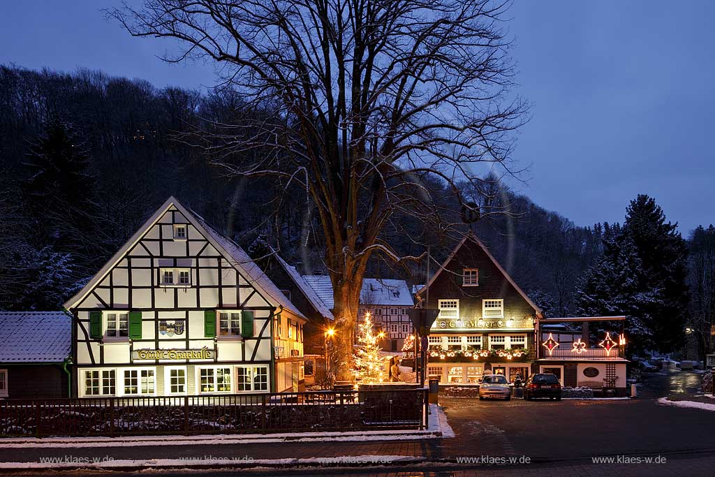 Solingen-Burg, Unterburg Weihnachtliche Stimmung zur blauen Stunde, beleuchteter Weihnachtsbaum, Fachwerkhaus alte Sparkasse, illuminiert und das verschieferte Cafe Meye rmit Burger Brezel auf dem Giebel; Solingen Burg, village Unterburg during Christmas time with Christmas tree and old half timbered bankhouse Sparkasse, illiminated