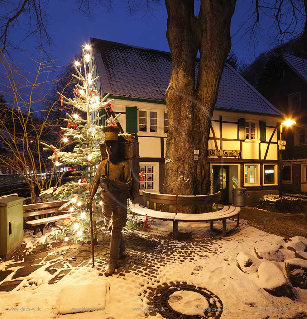 Solingen-Burg, Unterburg Weihnachtliche Stimmung zur blauen Stunde, beleuchteter Weihnachtsbaum, Bronze Skulptur Burger Brezelbaecker; Fachwerkhaus alte Sparkasse illuminiert; Solingen Burg, village Unterburg during Christmas time with pretzel bqaker and Christmas tree and old half timbered bankhouse Sparkasse, illuminated