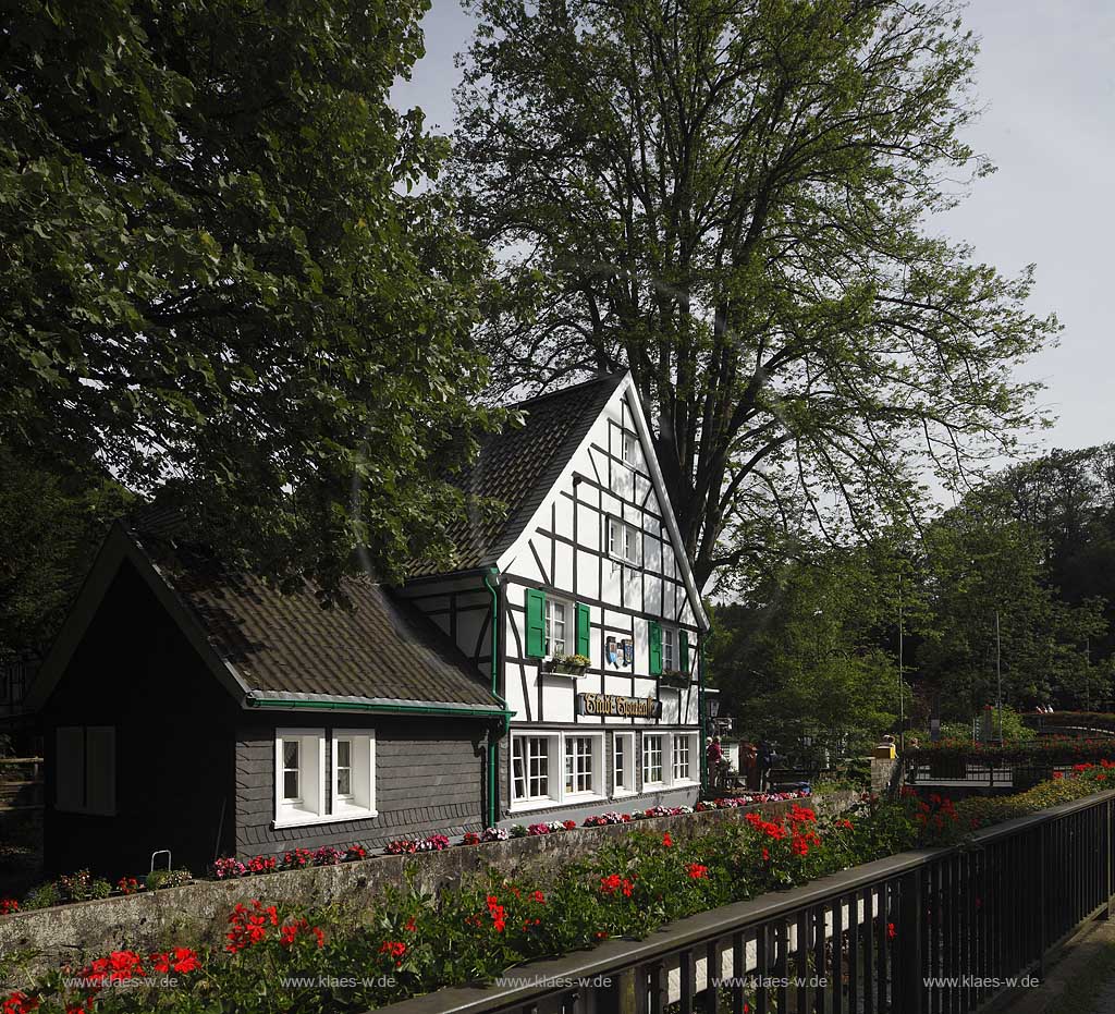 Solingen Unterburg, Schlossbergstrasse,bluehende Geranien im Vordergrund, Burger Brezelbaecker Denkmal, Stadtsparkasse Solingen und Cafe Meyer, Fachwerk- und Schieferhauser, Brezel auf dem Dach von dem Caf; Solingen-Unterburg, Schlossbergstrasse, blooming geranium , Burger pretzel baker historical monument, cafe Meyer, with frame houses and houses of shist, a pretzel is on the roof of the caf