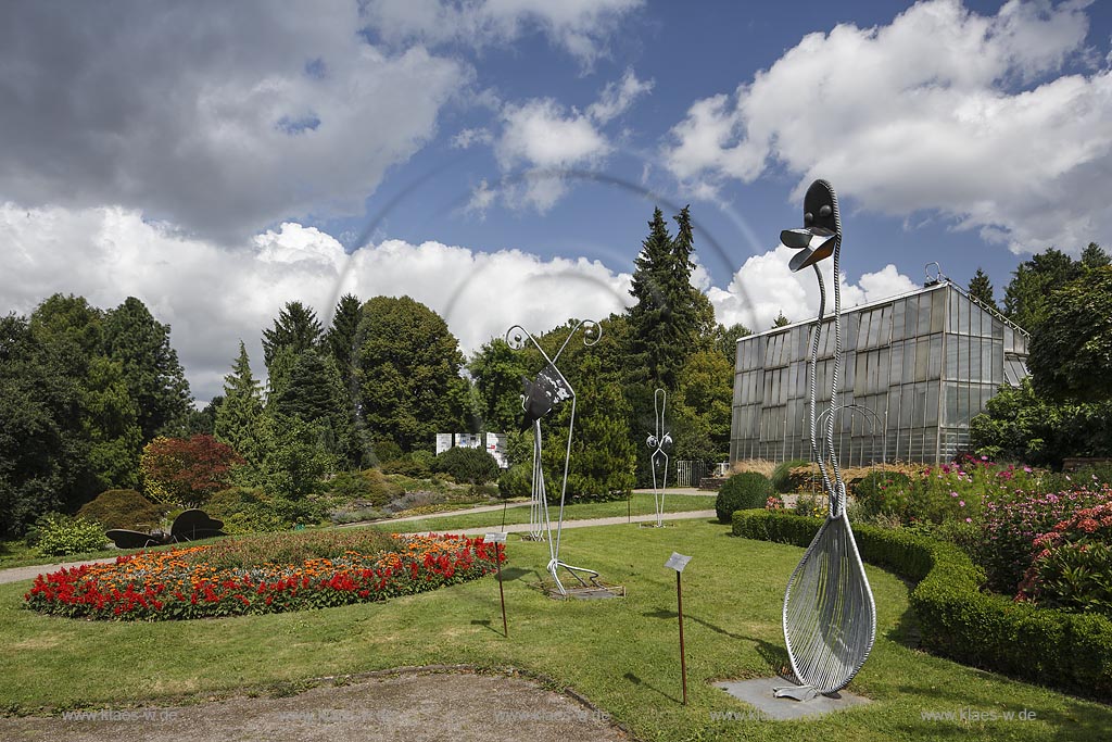 Solingen Wald, Blick in den Botanischen Garten im Sommer mit blauem Himmel und Wolken. Im Vordergrund verschiedene Skulpturen. Im Hintergrund das Tropenhaus. Solingen Wald, with a view to the Botanic garden at the Summer with blue Sky and Clouds. In the foreground different sculptures. In the Bachground the Tropic House.