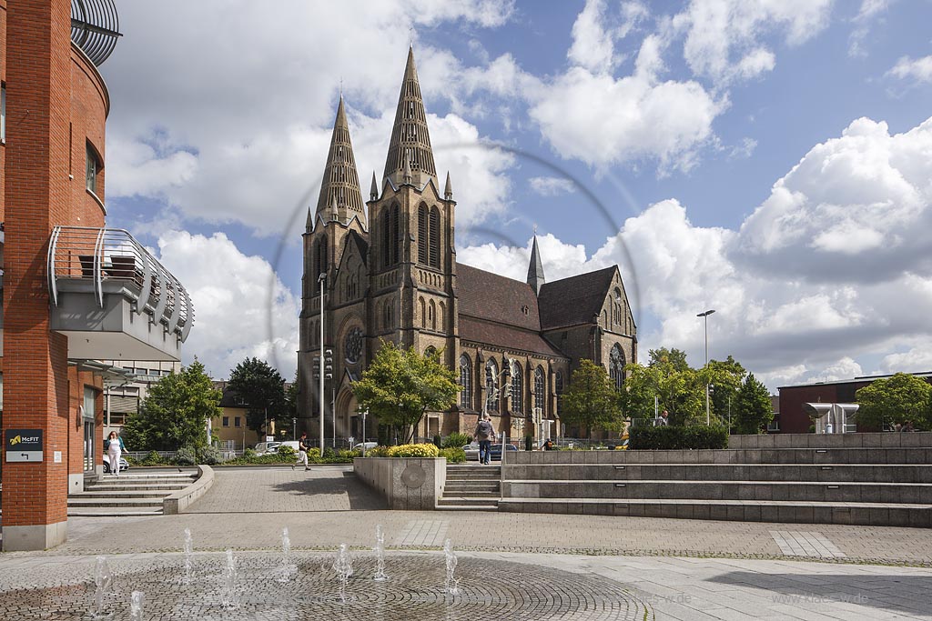 Solingen, Blick auf die St Clemens Kirche im Sommer mit blauem Himmel und Wolken, im Vordergrund Sicht auf den Muehlenplatz mit Springbrunnen und Fugaengern. Solingen, with a view to the Church St Clemens in Summer, with blue Sky and Clouds, in the foreground a view to the Muehlenplatz with a fountain and walkers.