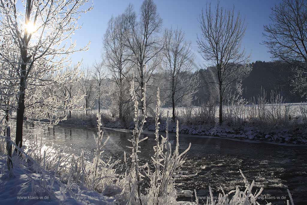 Der Fluss Agger bei Lohmar Wahlscheid an einem eisigen Wintertag verschneit mit Raureif im Gegenlicht mit Sonnenstern; the river Agger at a frosty winder day in snow covered landscape with hoarfrost in trees and gras with sunwhich lokks likes a star