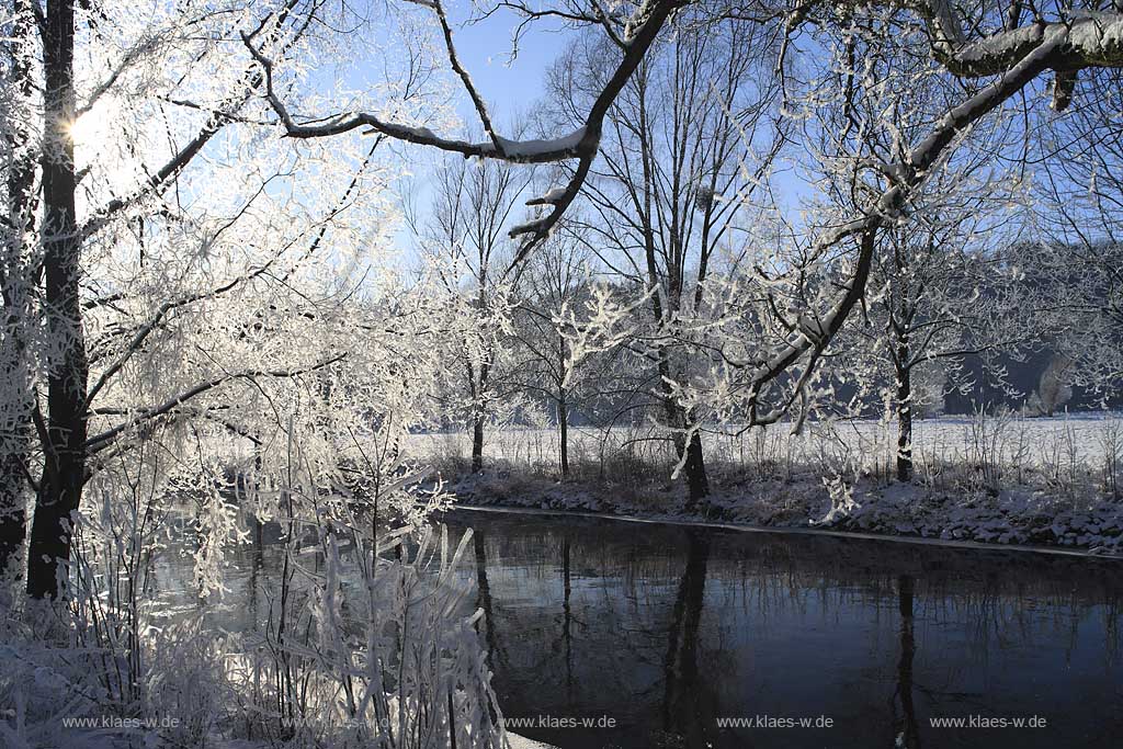 Der Fluss Agger bei Lohmar Wahlscheid an einem eisigen Wintertag verschneit mit Raureif im Gegenlicht mit Sonnenstern; the river Agger at a frosty winder day in snow covered landscape with hoarfrost in trees and gras with sunwhich lokks likes a star