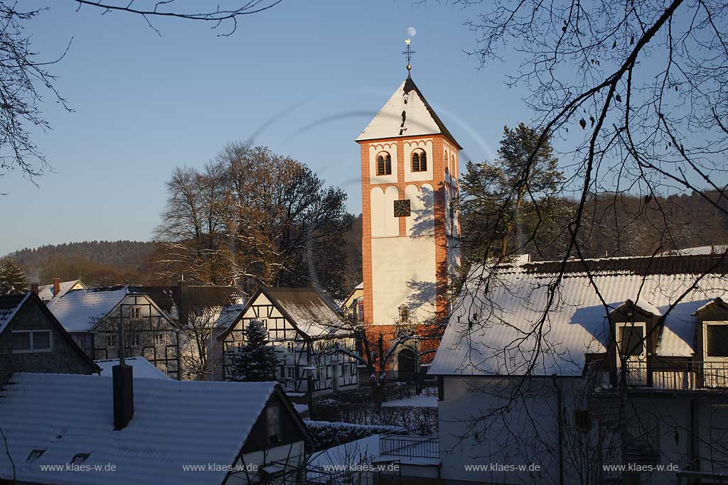 Odenthal Sankt Pankratius Pfarrkirche umgeben von Fachwerkhaeusern im Schnee im waremen Licht der untergehenden Abendsonne; St. Pankratius church with half-timbered houses in the surrounding in warm eveneing sunlight and snow.