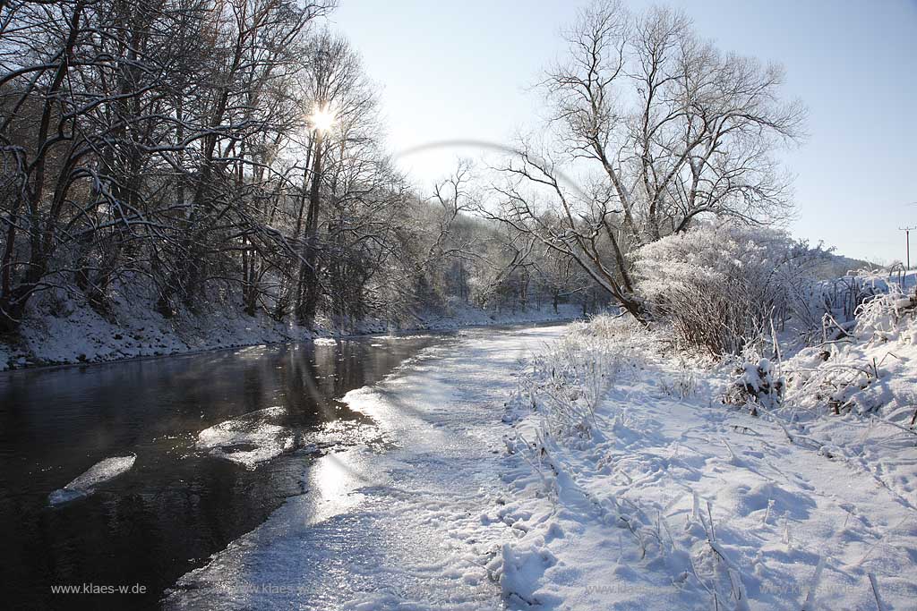 Der Fluss Agger bei Overath an einem eisigen Wintertag verschneit mit Raureif im Gegenlicht mit Sonnenstern; the river Agger at a frosty winder day in snow covered landscape with hoarfrost in trees and gras with sunwhich lokks likes a star