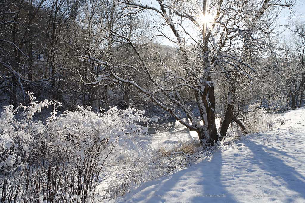 Der Fluss Agger bei Overath an einem eisigen Wintertag verschneit mit Raureif im Gegenlicht mit Sonnenstern; the river Agger at a frosty winder day in snow covered landscape with hoarfrost in trees and gras with sunwhich lokks likes a star