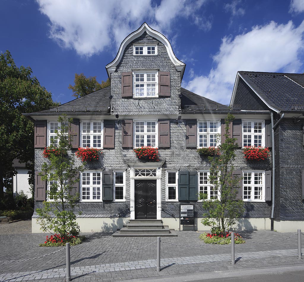 Wermelskirchen hisorisches Buergerhaus mit Schieferfassade und Giebel im Bergischen Stil Geranien Blumenschmuck an der Eich