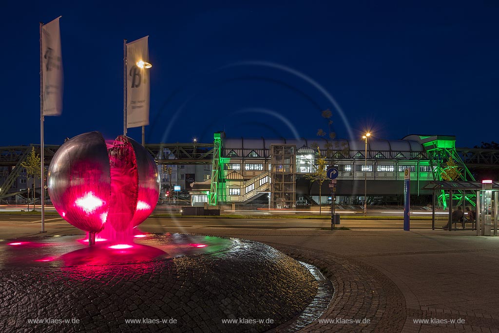 Wuppertal Barmen, Werth, Kugelbrunnen mit der Schwebebahnstation "Werther Bruecke" (im Hintergrund), illuminiert. Der 1979 von "Bert Gerresheim" erschaffene Brunnen beinhaltet 700 bronzene Figuren und 26 Reliefdarstellung und erzaehlt die Geschichte der Stadt; Wuppertal Barmen, Werth, kugel ball with station of the overhead railway (in the background) illuminated.