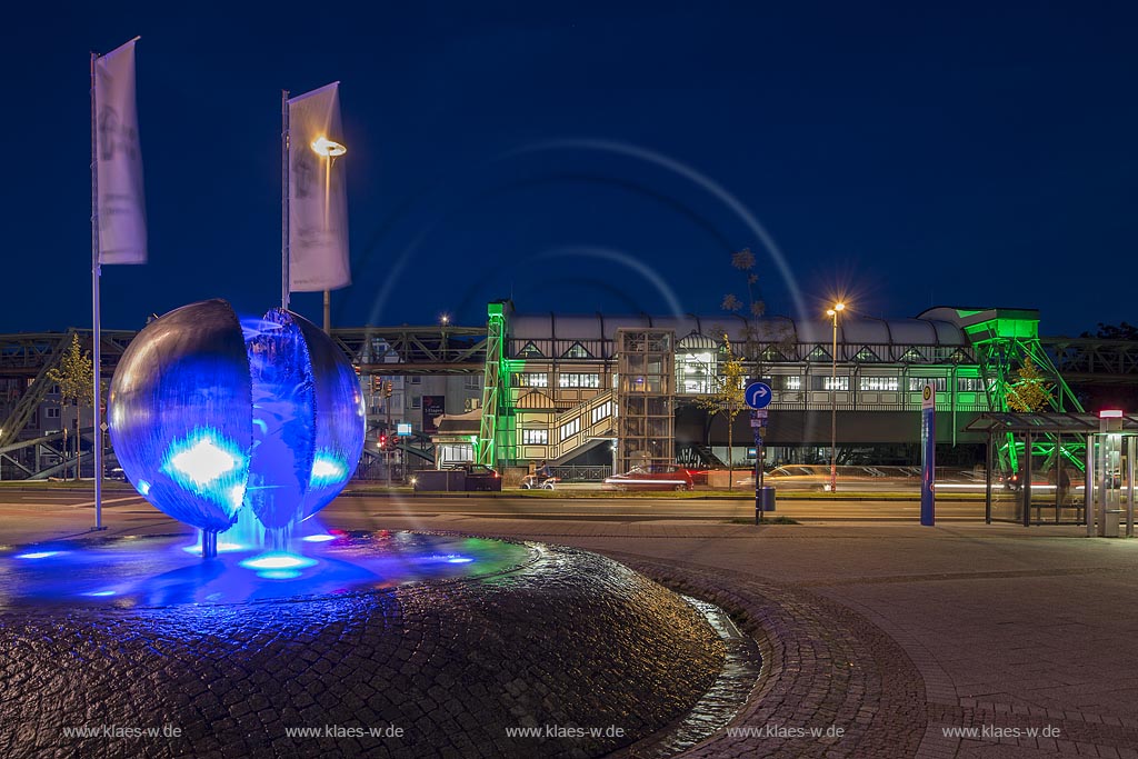 Wuppertal Barmen, Werth, Kugelbrunnen mit der Schwebebahnstation "Werther Bruecke" (im Hintergrund), illuminiert. Der 1979 von "Bert Gerresheim" erschaffene Brunnen beinhaltet 700 bronzene Figuren und 26 Reliefdarstellung und erzaehlt die Geschichte der Stadt; Wuppertal Barmen, Werth, kugel ball with station of the overhead railway (in the background) illuminated.