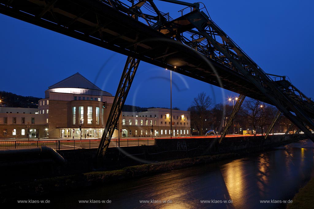 Wuppertal Barmen, das von innen beleuchtete Opernhaus nach dessen Renovierung vorn die Wupper und das Geruest der Schwebebahn im Fruehling zur blauen Stunde mit kahlen Baeumen, illuminiert; Wuppertal-Barmen Opera house with  in  springtime with the aereal tramway scaffolding and the river Wupper during blue hour