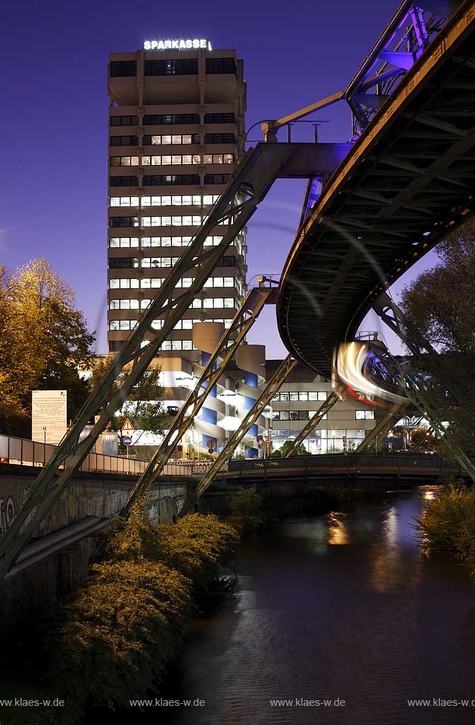 Wuppertal-Elberfeld Doeppersberg Blick mit Schwebebahn und Wupper zum Sparkassen Hochhaus mit Lichtinstallation Lichtwelle am Stahlgeruest zur blauen Stunde; Wuppertal-Elberfeld Doeppersberg aereal railway at blue hour, with illumination lightwave