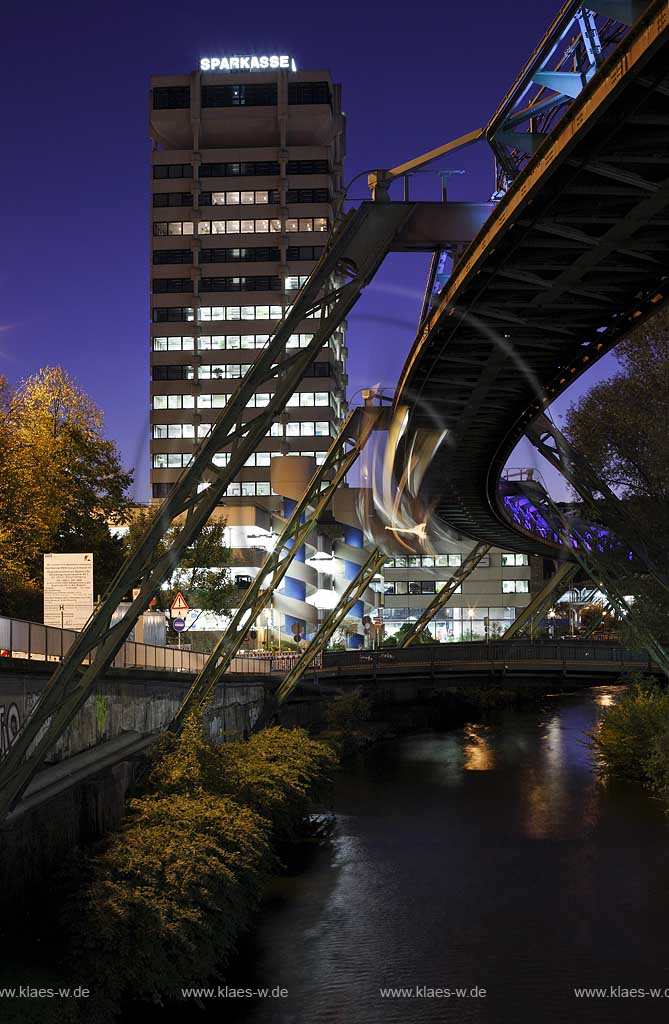 Wuppertal-Elberfeld Doeppersberg Blick mit Schwebebahn und Wupper zum Sparkassen Hochhaus mit Lichtinstallation Lichtwelle am Stahlgeruest zur blauen Stunde; Wuppertal-Elberfeld Doeppersberg aereal railway at blue hour, with illumination lightwave