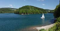 Aggertalsper, Blick von Sueden zur Halbinsel Burg Zinne zwischen dem Agger und Genkelarm, einem Segwelboot und dem Unnenbergturm am Horizont bei klarem Wetter mit blauem Himmel, wenigen Wolken in Fruehsommerlandschaft; Agger dam view over the barrage with a sailboat in summer landscape, Unnenberg look out at the horizon, blue sky few clouds