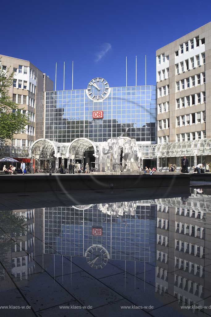 Blick auf den Hauptbahnhof in Dsseldorf, Duesseldorf-Innenstadt mit Sicht auf Skulpturen und Menschen und Spiegelbild vom Bahnhofsgebaeude im Teich