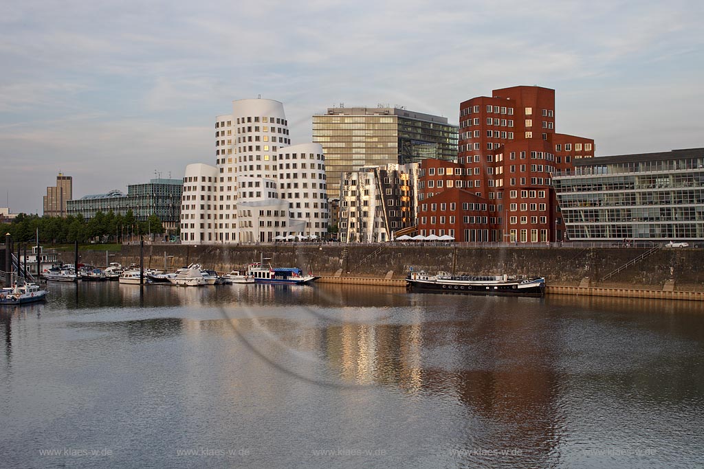 Duesseldorf Hafen, Neuer Zollhof und Rheinturm, Frank O. Gehry Bauten: Zollhof 3 weisse Fassade, Zollhof 2 Spiegelfassade, Zollhof 1 Bachsteinfasseade. Die Gebaeude zeigen weder Gesimse noch Sockel. Auffallend ist die Kruemmung der Fassade mit einer fliessend, gewellten Oberflaeche, im Hintergrund das Stadttor, Abendstimmung, stimmungsvoll; Duesseldorf Hafen, buildings of Frank O. Gehry