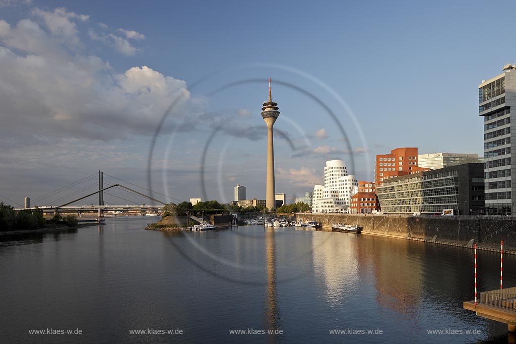 Duesseldorf Hafen, Medienhafen Panoramablick mit Rhein, neuer Fussgaegerbruecke. Rheinturm, 3 Frank O. Gehry Bauten: Zollhof 3 weisse Fassade, Zollhof 2 Spiegelfassade, Zollhof 1, Backsteinfassade,  angstrahlt vom Licht der untergehenden Sonne; Duesseldorf-Hafen, mediaport panoramaview with rhine, new pedestrian bridge, rhinetower, Frank O. Gehry buildings duty yard 3 with white facade, duty yard 2 with mirror facade, duty yard 1 with clinker facade during evening sunset light
