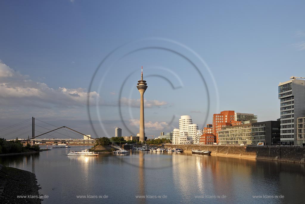 Duesseldorf Hafen, Medienhafen Panoramablick mit Rhein, neuer Fussgaegerbruecke. Rheinturm, 3 Frank O. Gehry Bauten: Zollhof 3 weisse Fassade, Zollhof 2 Spiegelfassade, Zollhof 1, Backsteinfassade,  angstrahlt vom Licht der untergehenden Sonne; Duesseldorf-Hafen, mediaport panoramaview with rhine, new pedestrian bridge, rhinetower, Frank O. Gehry buildings duty yard 3 with white facade, duty yard 2 with mirror facade, duty yard 1 with clinker facade during evening sunset light