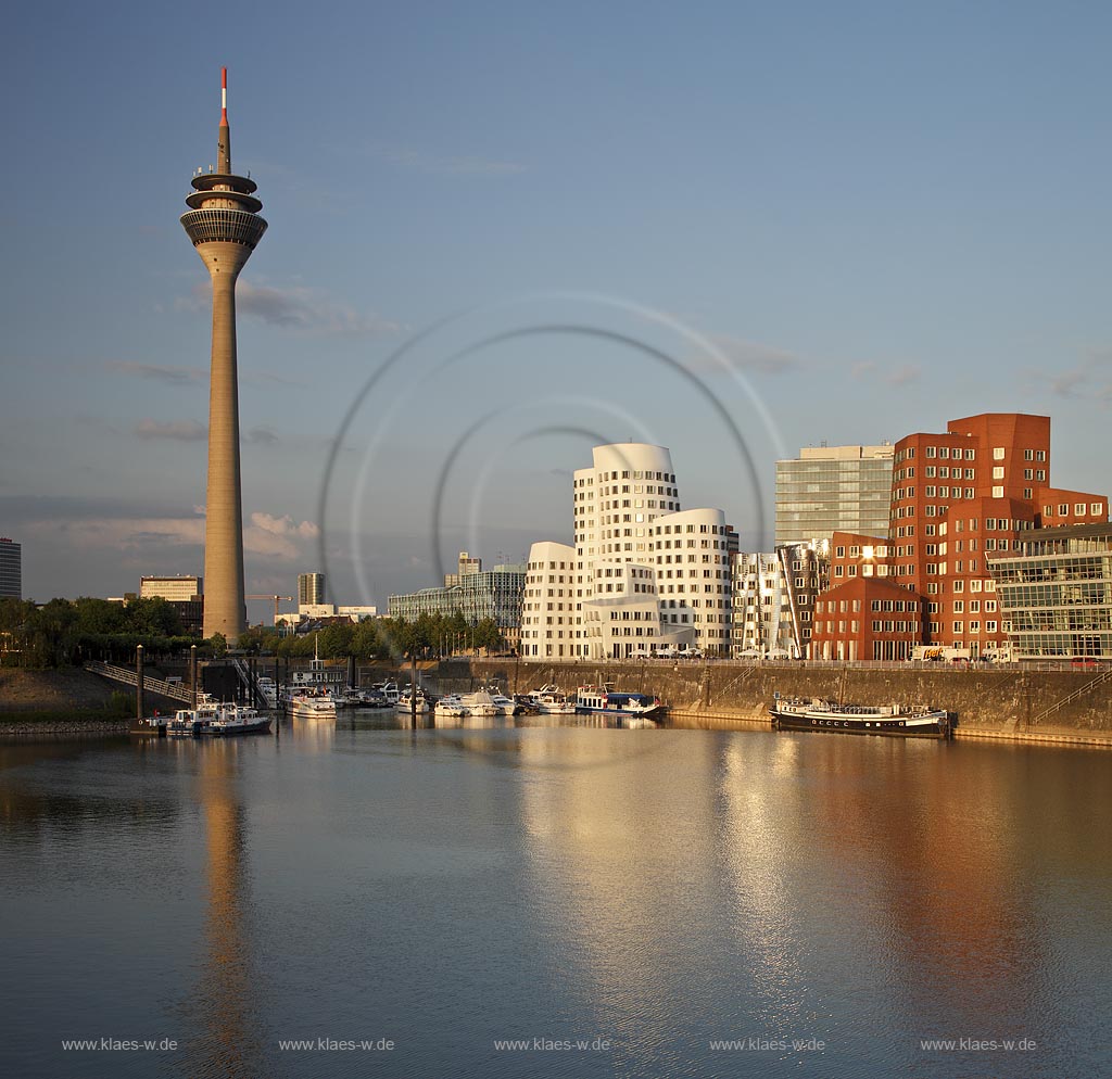 Duesseldorf Hafen, Medienhafen Panoramablick mit Rhein, neuer Fussgaegerbruecke. Rheinturm, 3 Frank O. Gehry Bauten: Zollhof 3 weisse Fassade, Zollhof 2 Spiegelfassade, Zollhof 1, Backsteinfassade,  angstrahlt vom Licht der untergehenden Sonne; Duesseldorf-Hafen, mediaport panoramaview with rhine, new pedestrian bridge, rhinetower, Frank O. Gehry buildings duty yard 3 with white facade, duty yard 2 with mirror facade, duty yard 1 with clinker facade during evening sunset light