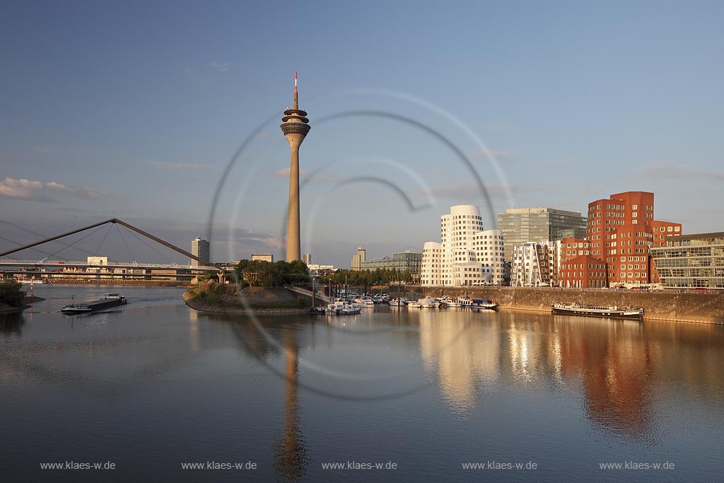 Duesseldorf Hafen, Medienhafen Panoramablick mit Rhein, neuer Fussgaegerbruecke. Rheinturm, 3 Frank O. Gehry Bauten: Zollhof 3 weisse Fassade, Zollhof 2 Spiegelfassade, Zollhof 1, Backsteinfassade,  angstrahlt vom Licht der untergehenden Sonne; Duesseldorf-Hafen, mediaport panoramaview with rhine, new pedestrian bridge, rhinetower, Frank O. Gehry buildings duty yard 3 with white facade, duty yard 2 with mirror facade, duty yard 1 with clinker facade during evening sunset light