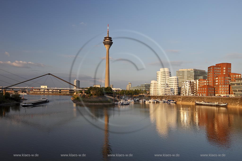 Duesseldorf Hafen, Medienhafen Panoramablick mit Rhein, neuer Fussgaegerbruecke. Rheinturm, 3 Frank O. Gehry Bauten: Zollhof 3 weisse Fassade, Zollhof 2 Spiegelfassade, Zollhof 1, Backsteinfassade,  angstrahlt vom Licht der untergehenden Sonne; Duesseldorf-Hafen, mediaport panoramaview with rhine, new pedestrian bridge, rhinetower, Frank O. Gehry buildings duty yard 3 with white facade, duty yard 2 with mirror facade, duty yard 1 with clinker facade during evening sunset light