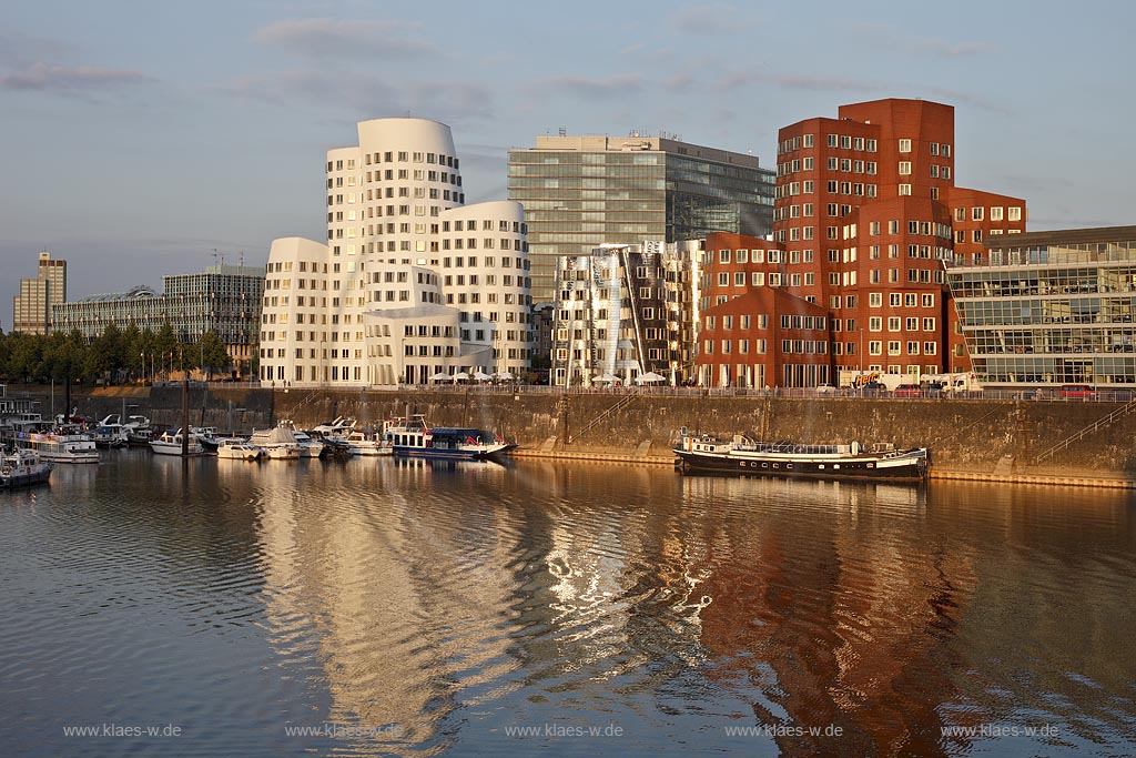 Duesseldorf Hafen, Medienhafen,3 Frank O. Gehry Bauten: Zollhof 3 weisse Fassade, Zollhof 2 Spiegelfassade, Zollhof 1, Backsteinfassade, dahinter das Stadttor, neues Wahrzeichen der Stadt, angstrahlt vom Licht der untergehenden Sonne; Duesseldorf-Hafen, 3 Frank O. Gehry buildings: duty yard 3 with white facade, duty yard 2 with mirror facade, duty yard 1 with clinker facade during evening sunset light