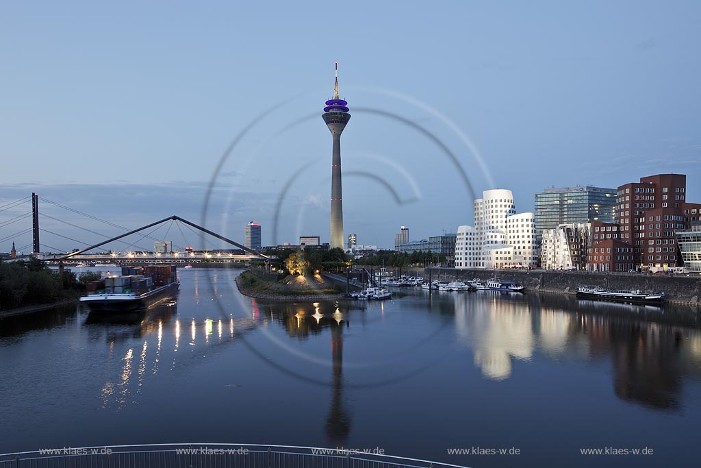 Duesseldorf Hafen, Medienhafen Panoramablick mit Rhein, neuer Fussgaegerbruecke. Rheinturm, 3 Frank O. Gehry Bauten: Zollhof 3 weisse Fassade, Zollhof 2 Spiegelfassade, Zollhof 1, Backsteinfassade,  illuminiert waehrend der blauen Stunde; Duesseldorf-Hafen, mediaport panoramaview with rhine, new pedestrian bridge,rhinetower, Frank O. Gehry buildings duty yard 3 with white facade, duty yard 2 with mirror facade, duty yard 1 with clinker facade illuminated during blue hour