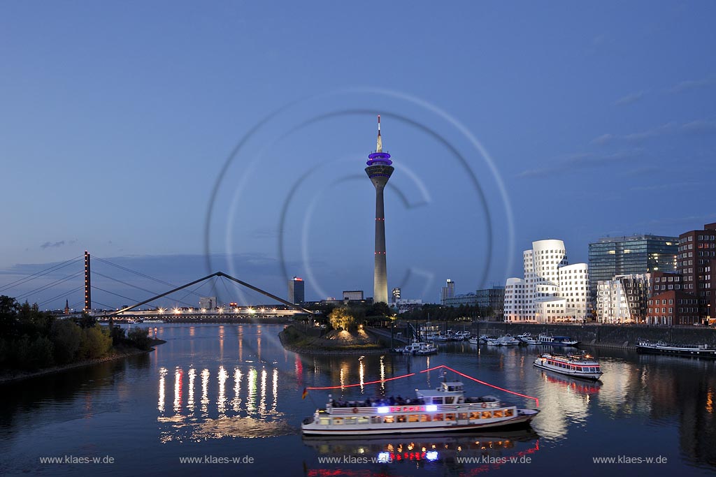 Duesseldorf Hafen, Medienhafen Panoramablick mit Rhein, neuer Fussgaegerbruecke. Rheinturm, 3 Frank O. Gehry Bauten: Zollhof 3 weisse Fassade, Zollhof 2 Spiegelfassade, Zollhof 1, Backsteinfassade,  illuminiert waehrend der blauen Stunde; Duesseldorf-Hafen, mediaport panoramaview with rhine, new pedestrian bridge,rhinetower, Frank O. Gehry buildings duty yard 3 with white facade, duty yard 2 with mirror facade, duty yard 1 with clinker facade illuminated during blue hour