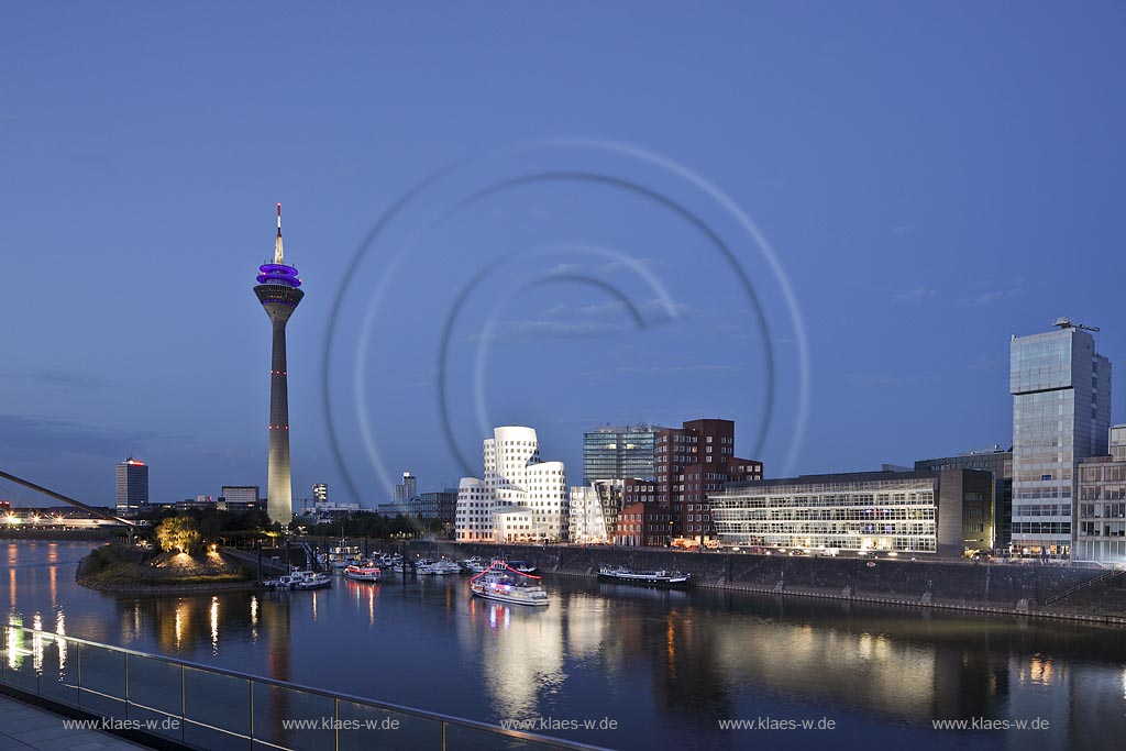 Duesseldorf Hafen, Medienhafen Panoramablick mit Rhein, neuer Fussgaegerbruecke. Rheinturm, 3 Frank O. Gehry Bauten: Zollhof 3 weisse Fassade, Zollhof 2 Spiegelfassade, Zollhof 1, Backsteinfassade,  illuminiert waehrend der blauen Stunde; Duesseldorf-Hafen, mediaport panoramaview with rhine, new pedestrian bridge,rhinetower, Frank O. Gehry buildings duty yard 3 with white facade, duty yard 2 with mirror facade, duty yard 1 with clinker facade illuminated during blue hour