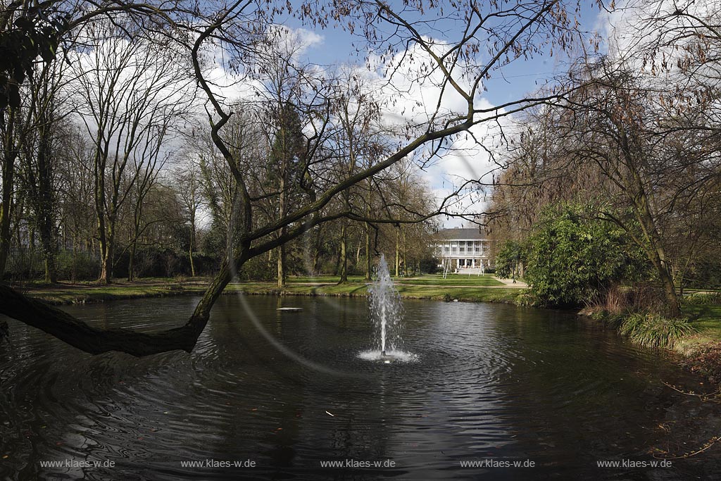 Duesseldorf Pempefort Malkastengarten, Jacobigarten Venusteich mit Wasserfontaene im Fruehling mit kahlen Baeumen und Spiegelbild, Blick it Mittelachse zum Hentrichaus; Duesseldorf Pempelfort Jacobigarden with pond Venusteich in springtime