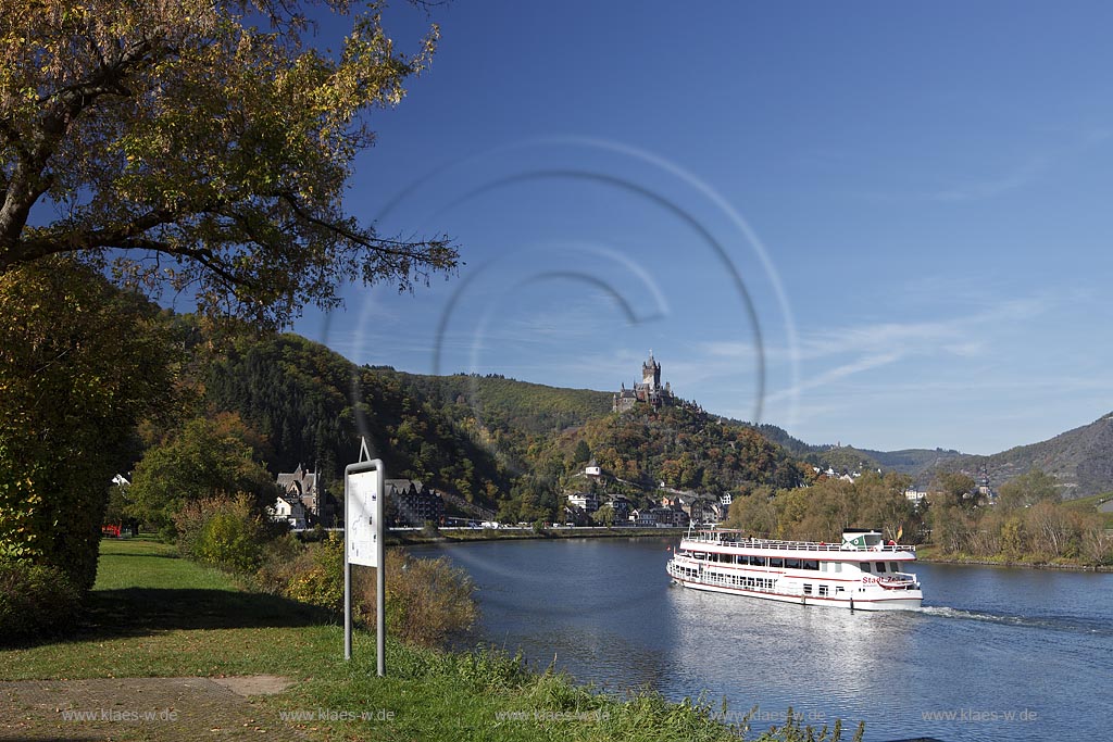 Cochem, Blick vom Moselufer ueber den Fluss mit Passagierschiff zur Reichsburg in Herbstlandschaft; Cochem, view from Moselle riverfront with cruise vessel on river onto castle Reichsburg in autumn landscape