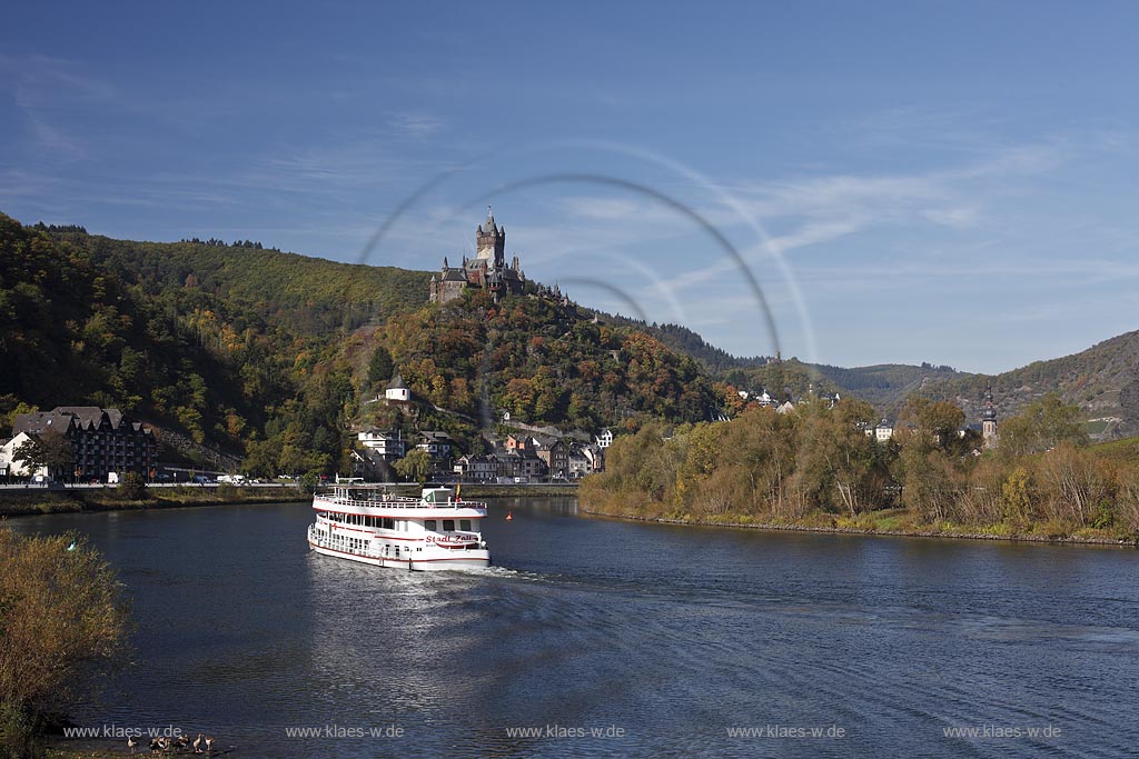 Cochem, Blick vom Moselufer ueber den Fluss mit Passagierschiff zur Reichsburg in Herbstlandschaft; Cochem, view from Moselle riverfront with cruise vessel on river onto castle Reichsburg in autumn landscape