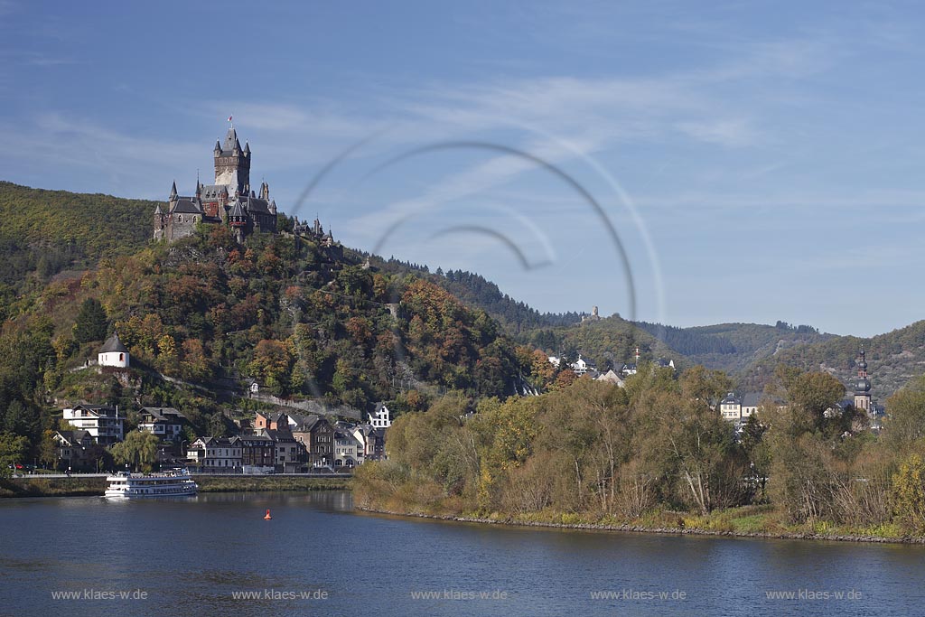 Cochem, Blick vom Moselufer ueber den Fluss mit Passagierschiff zur Reichsburg in Herbstlandschaft; Cochem, view from Moselle riverfront with cruise vessel on river onto castle Reichsburg in autumn landscape