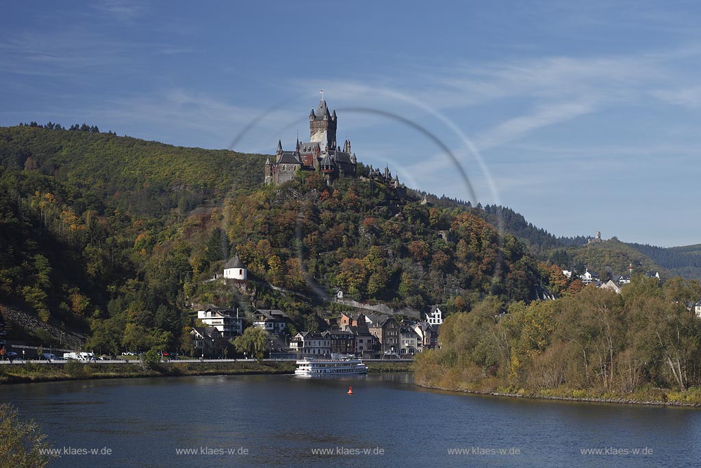 Cochem, Blick vom Moselufer ueber den Fluss mit Passagierschiff zur Reichsburg in Herbstlandschaft; Cochem, view from Moselle riverfront with cruise vessel on river onto castle Reichsburg in autumn landscape