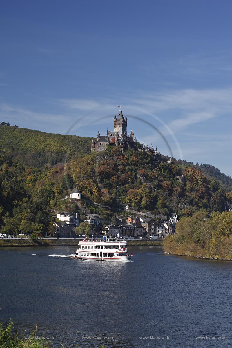 Cochem, Blick vom Moselufer ueber den Fluss mit Passagierschiff zur Reichsburg in Herbstlandschaft; Cochem, view from Moselle riverfront with cruise vessel on river onto castle Reichsburg in autumn landscape