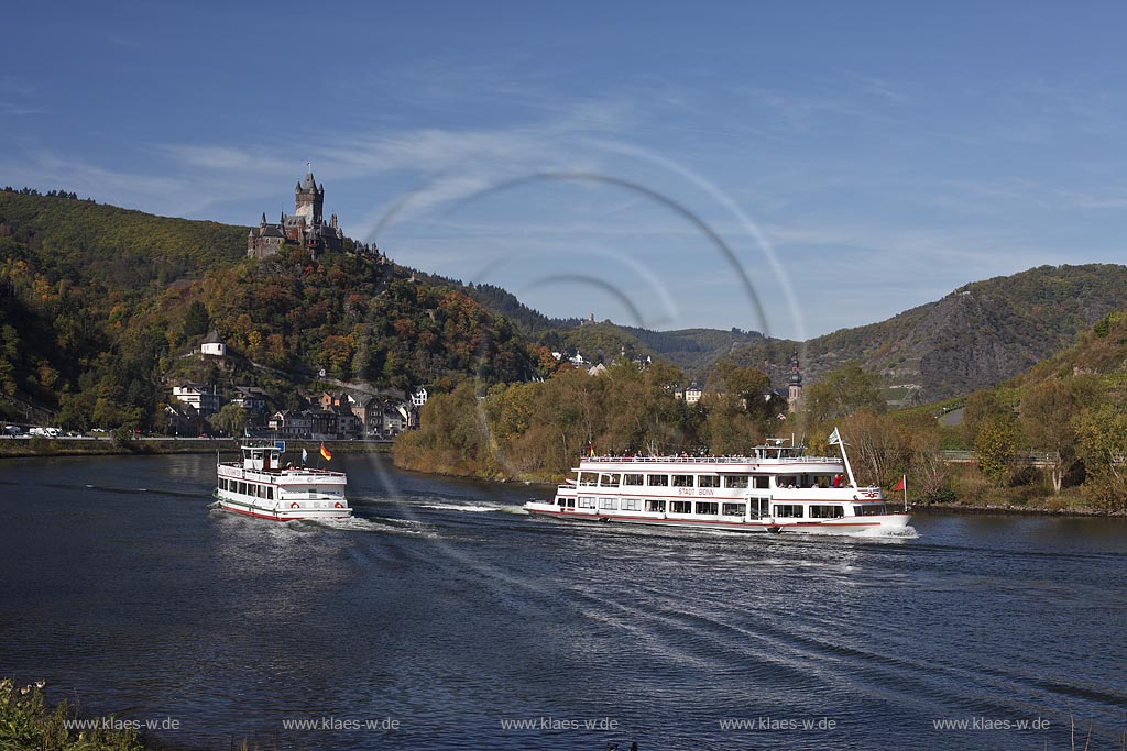 Cochem, Blick vom Moselufer ueber den Fluss mit zwei Passagierschiffen zur Reichsburg in Herbstlandschaft; Cochem, view from Moselle riverfront with two cruise vessels on river onto castle Reichsburg in autumn landscape