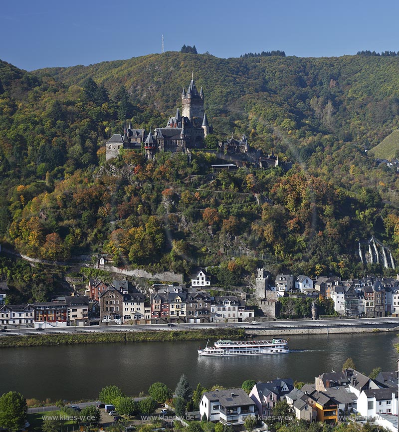 Cochem, Blick ueber die Mosel mit Ausflugsschiff zur Reichsburg mit Stadt Cochem in Herbstlandschaft; Cochem, view over Moselle river with cruise vessel onto Cochem with castle Reichsburg in autumn landscape.