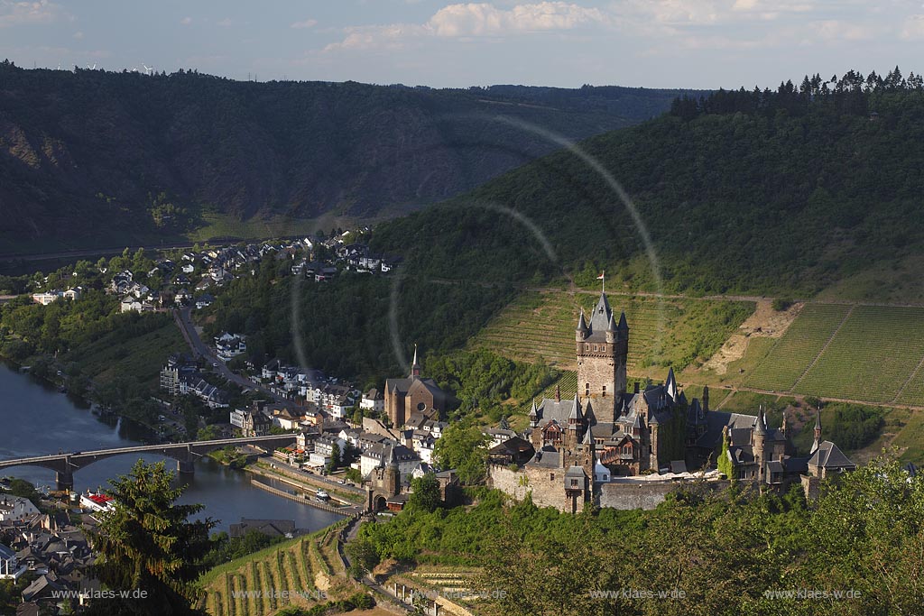 Blick auf Cochem mit Mosel und Reichsburg, die Wahrzeichen von Cochem ist und  auf einem weithin sichtbaren Bergkegel mehr als 100 Meter oberhalb der Stadt steht. Als Gipfelburg gehoert sie zum Typus der Hoehenburgen; view to Cochem with Moselle and Reichsburg.