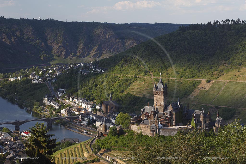 Blick auf Cochem mit Mosel und Reichsburg, die Wahrzeichen von Cochem ist und  auf einem weithin sichtbaren Bergkegel mehr als 100 Meter oberhalb der Stadt steht. Als Gipfelburg gehoert sie zum Typus der Hoehenburgen; view to Cochem with Moselle and Reichsburg.