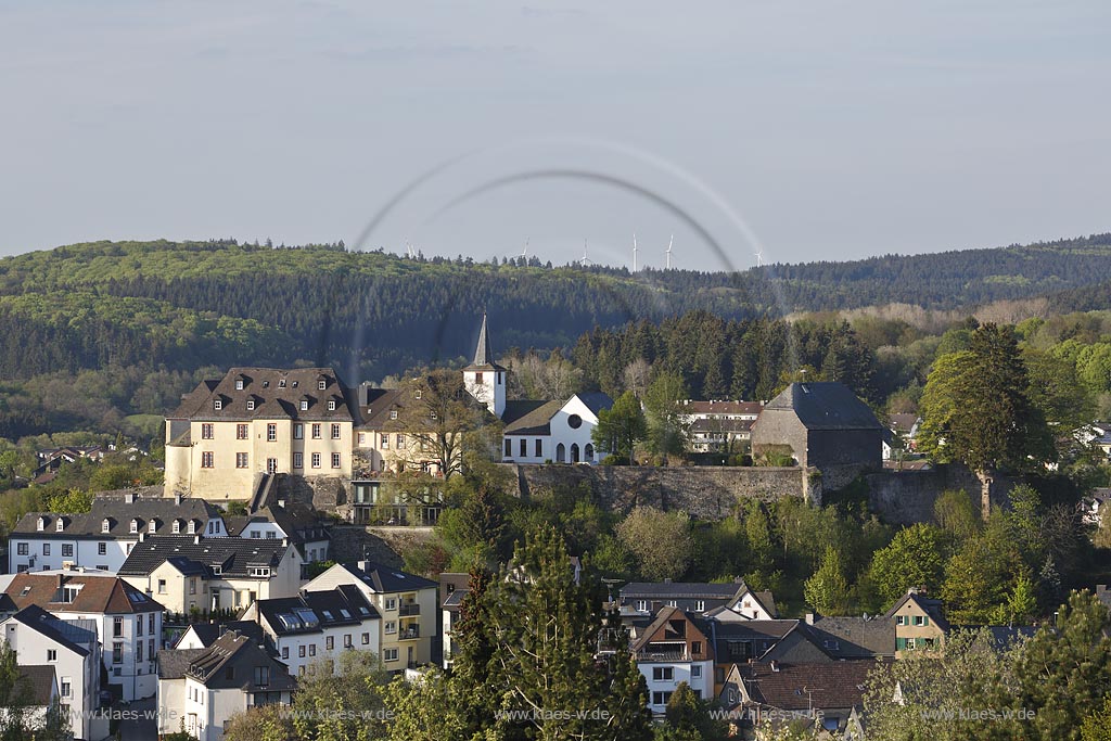 Daun, Stadtpanorama mit Resten der Umfassungsmauern der wohl hochmittelalterlichen, 1689 zerstoerten Burganlage, links im Bild ehemaliges kurtrierisches Amtshaus, rechts dahinter die evangelische neugotische Kirche, rechts Kueppelwalmdachscheune; Daun, panorama of the town with the rest of the enclosure wall of the castle and at the left side the once deanery and behind it  the evangelic church.