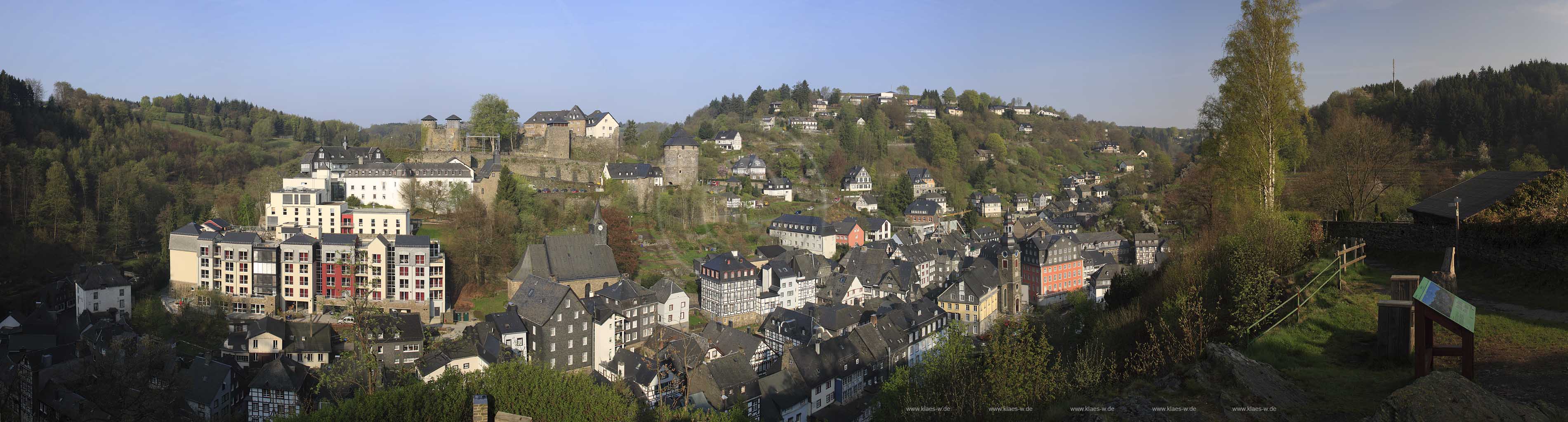 Monschau, extrem Panorama Blick vom Kierberg auf Monschau mit den markenten Gebaueden von links nach rechts: Burg Monschau, katholische Pfarrkirche Sankt Mariae Geburt und Sankt Josef, Altstadt, evangelische Kirche, Rotes Haus im Fruehling; Extreme panorama view from the hill kierberg to the village Monschau with the castle, catholic church St. Marie born and St. Joseph, old town, evangelic church and red house