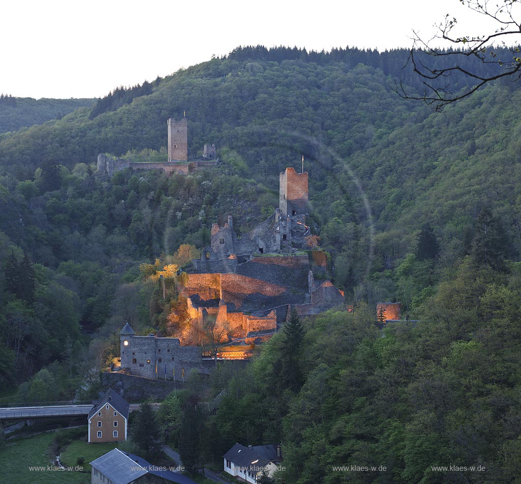 Manderscheid, Blick vom Eifelsteig auf die Ruinen, Burgruine Niederburg vorne rechts und Oberburg hinten links im Bild in Abenstimmung, illuminirt, blaue Stunde; Manderscheid, view onto castle ruines Niederburg, right side in front and Oberburg, left side in rear in the evening during blue hour, illuminated.