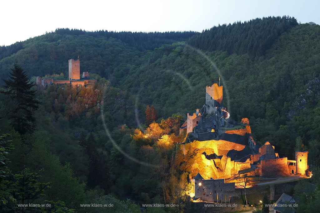 Manderscheid, Blick vom Eifelsteig auf die Ruinen, Burgruine Niederburg vorne rechts und Oberburg hinten links im Bild in Abenstimmung, illuminirt, blaue Stunde; Manderscheid, view onto castle ruines Niederburg, right side in front and Oberburg, left side in rear in the evening during blue hour, illuminated.