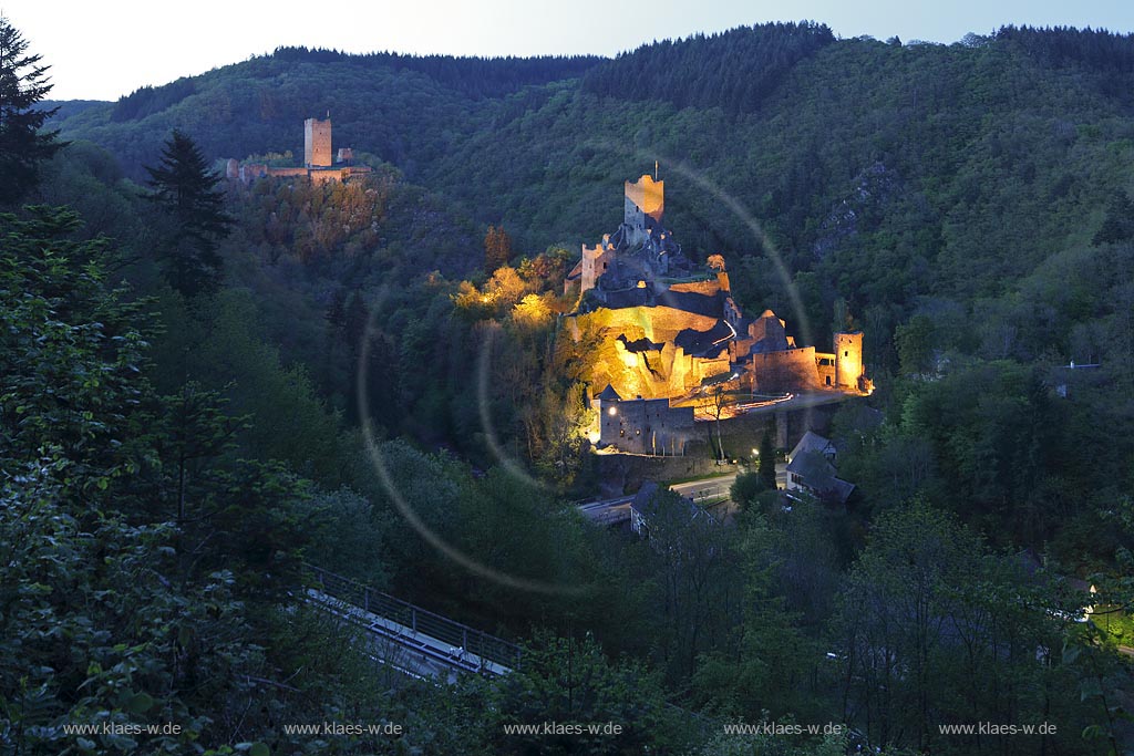 Manderscheid, Blick vom Eifelsteig auf die Ruinen, Burgruine Niederburg vorne rechts und Oberburg hinten links im Bild in Abenstimmung, illuminirt, blaue Stunde; Manderscheid, view onto castle ruines Niederburg, right side in front and Oberburg, left side in rear in the evening during blue hour, illuminated.