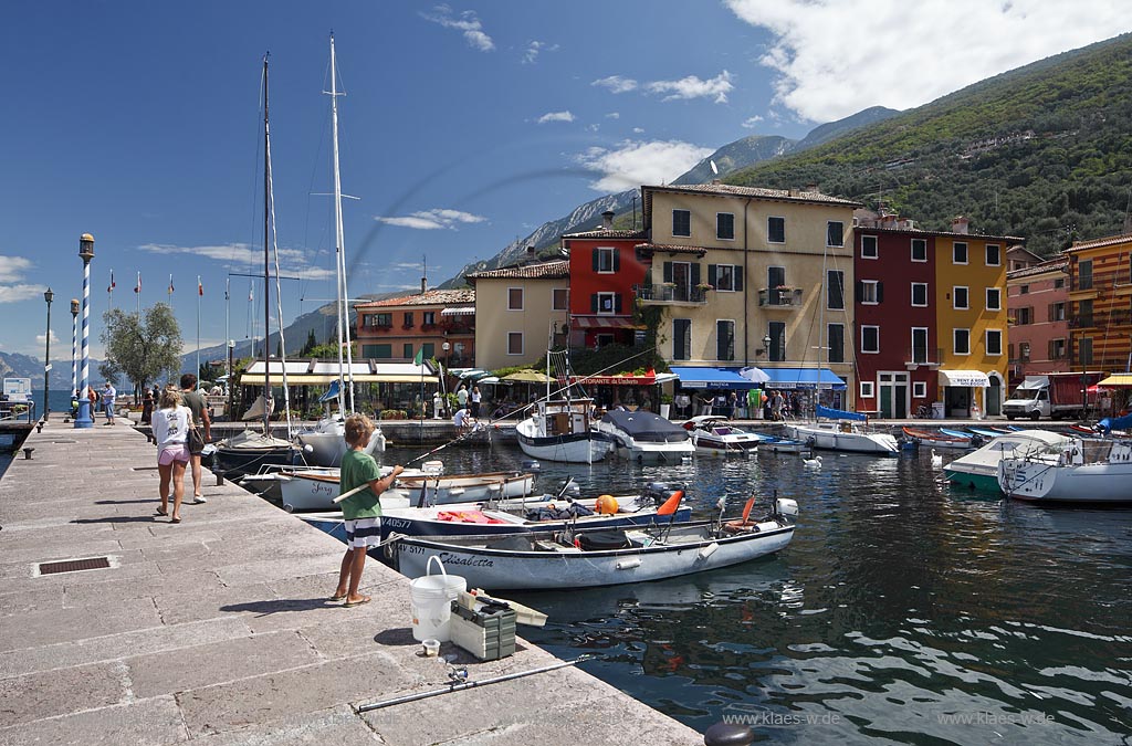 Castelletto Di Brenzone, Blick von der Hafenmole mit Angler ueber Hafen mit Fischerbooten auf bunte Haeuser; Castelletto Di Brenzone, view from the mole with angler over the port with fishing boats to old prettily pointed houses